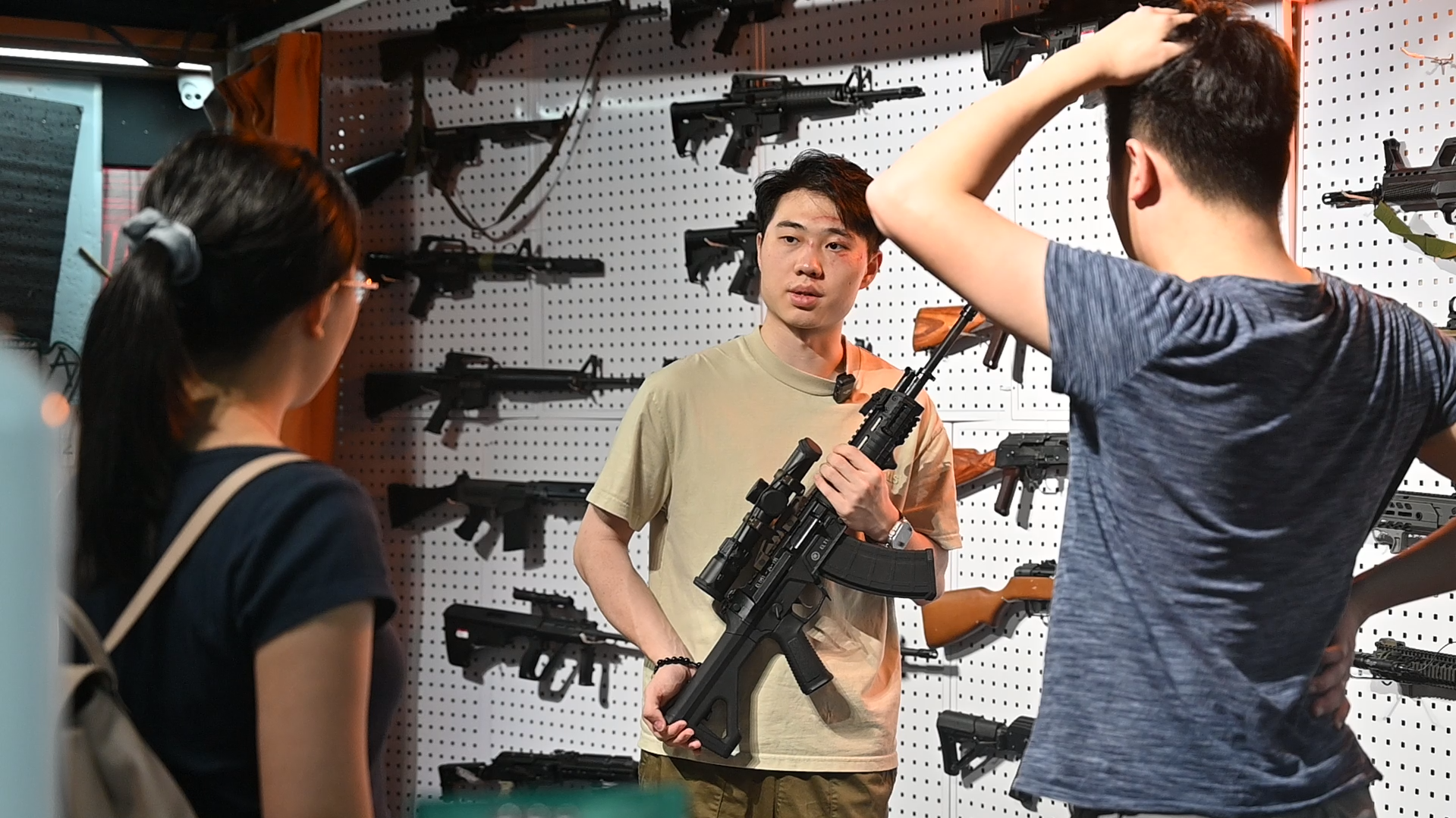 Allen Lui (middle) introducing one of the signature items for mainland tourists, the E&L 191 gas blowback rifle, a replica of China’s PLA’s latest standard-issue weapon. Credit: Yang Yihua